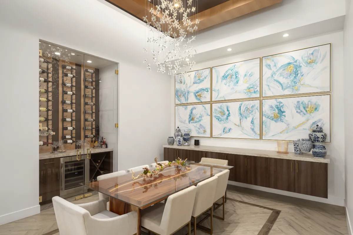 Dining room with a glass-topped wood table, floral art wall and a glass-enclosed wine room