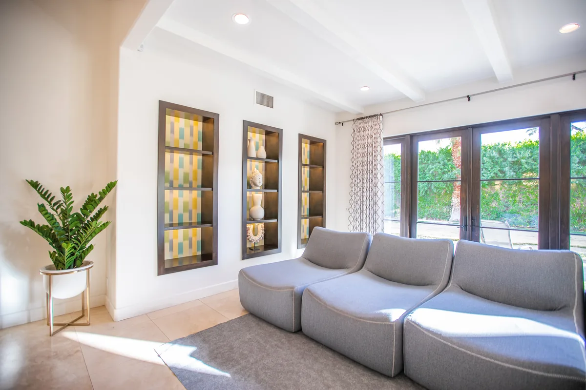 Living room with three lit display niches in dark timber surrounds beside a low grey sectional