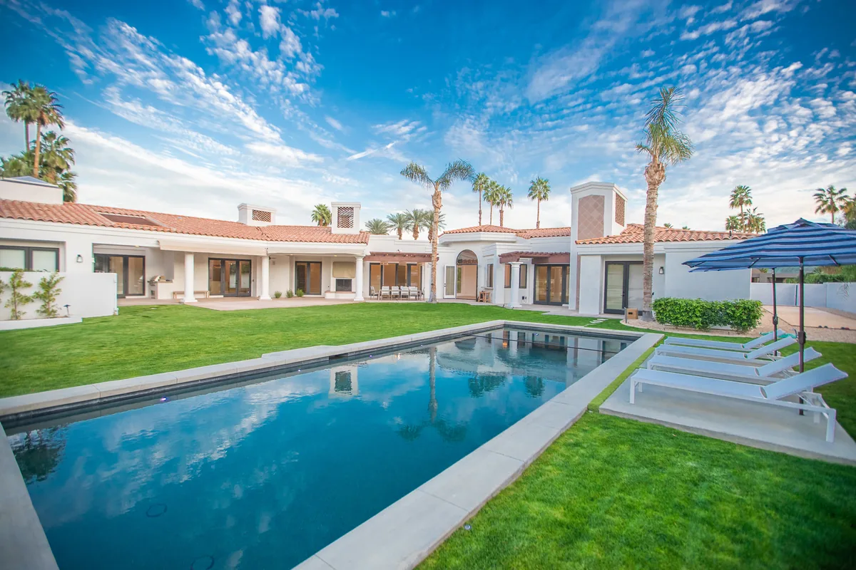 Mediterranean estate with a red tile roof, arcaded loggia and a long rectangular pool set in lawn
