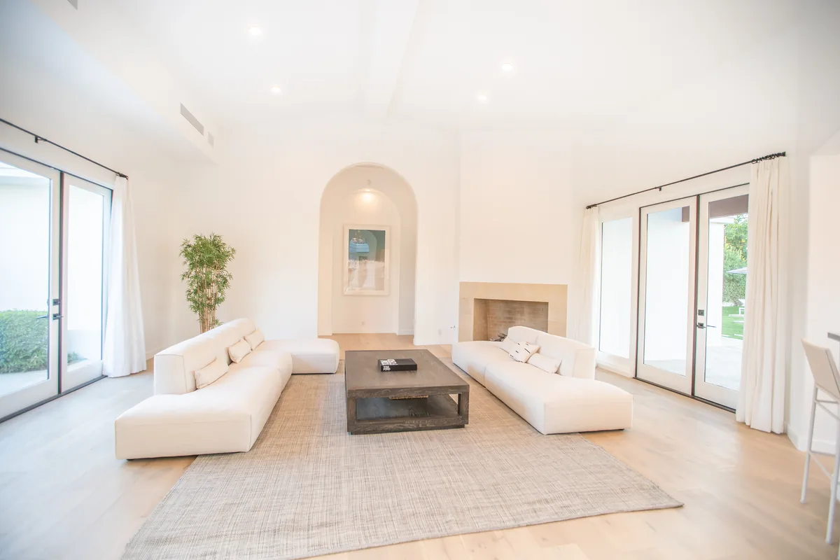 Sitting room with a plaster fireplace, vaulted ceiling and light oak floors