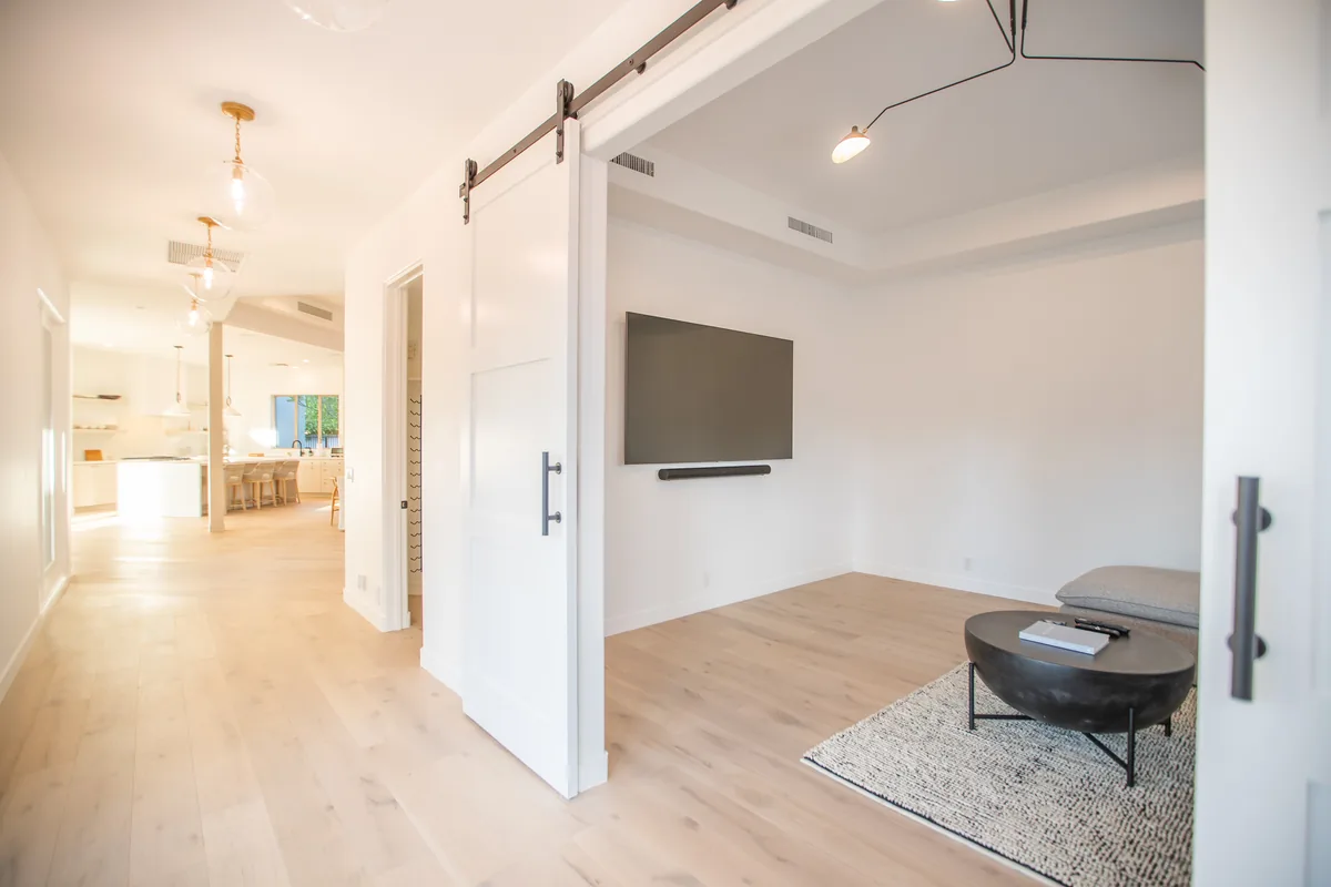Great room with a sliding barn door, pale oak floors and a wall-mounted television