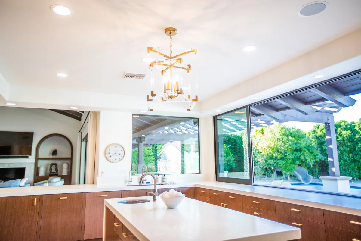 Kitchen island looking through a wide opening to the covered patio and pool beyond