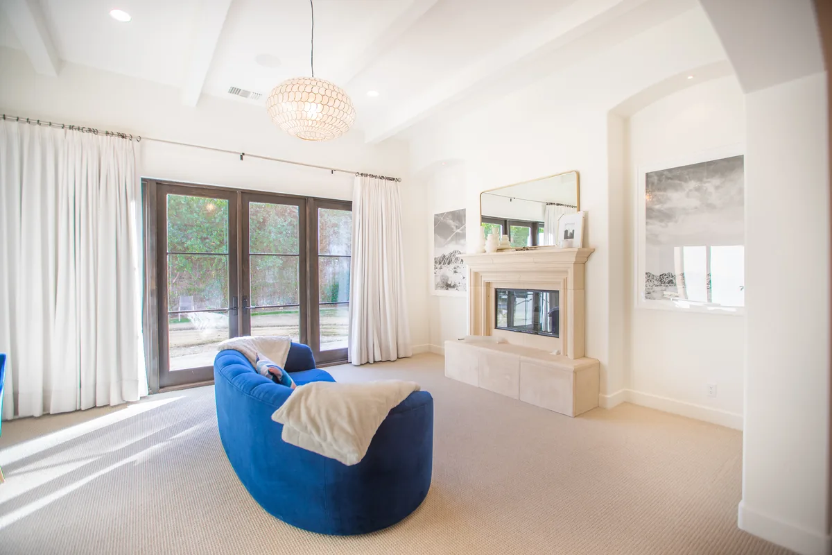 Living room with a stone fireplace, curved blue sofa and French doors to the garden