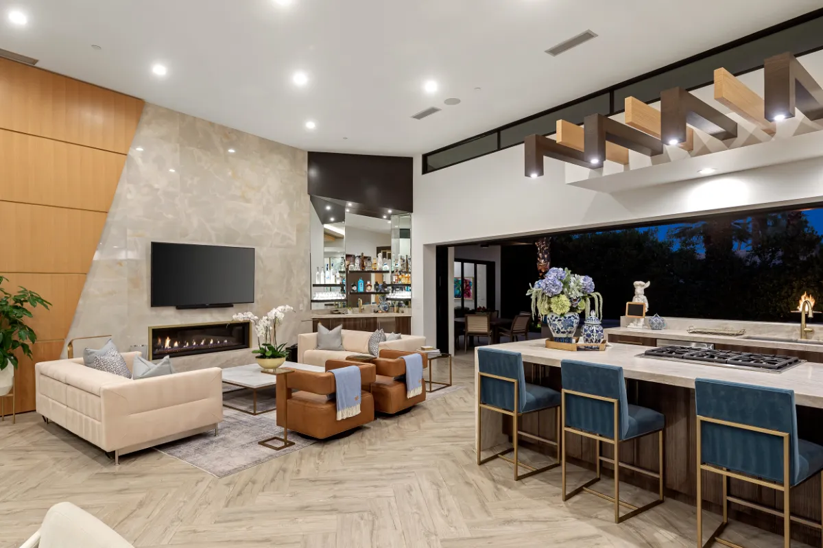 Remodeled open living room and kitchen with a linear fireplace and marble island seating