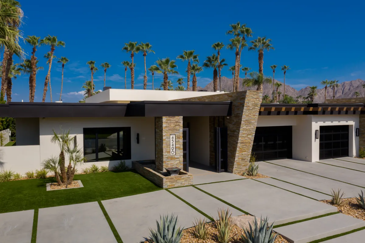 Front elevation of a desert modern home with stacked stone columns and a wide concrete driveway