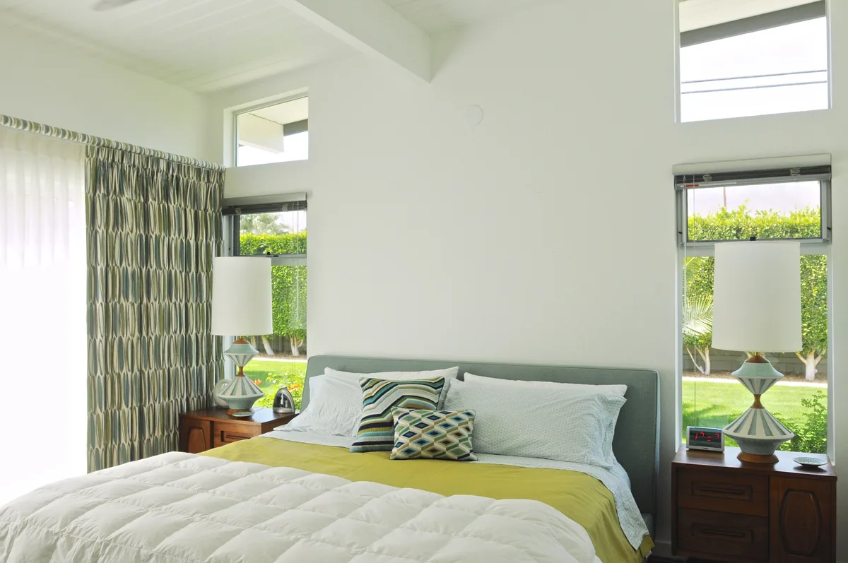 Bedroom with clerestory windows, patterned drapery and a low upholstered bed