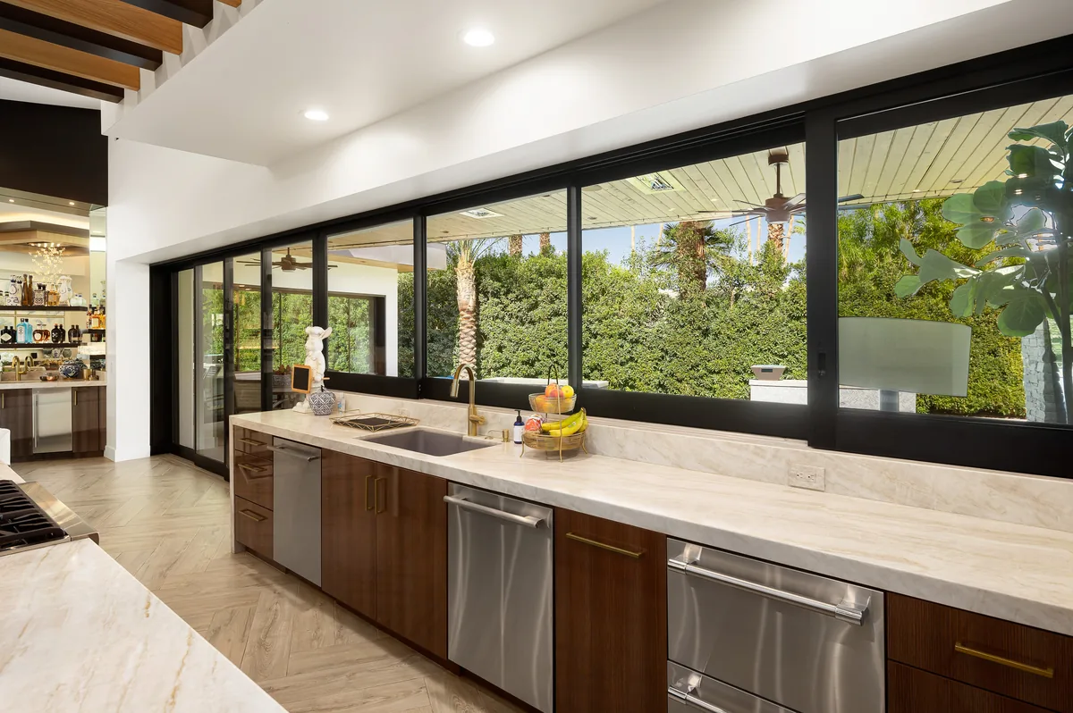 Kitchen and bar with a full wall of glass slid open to the pool deck and mountain view