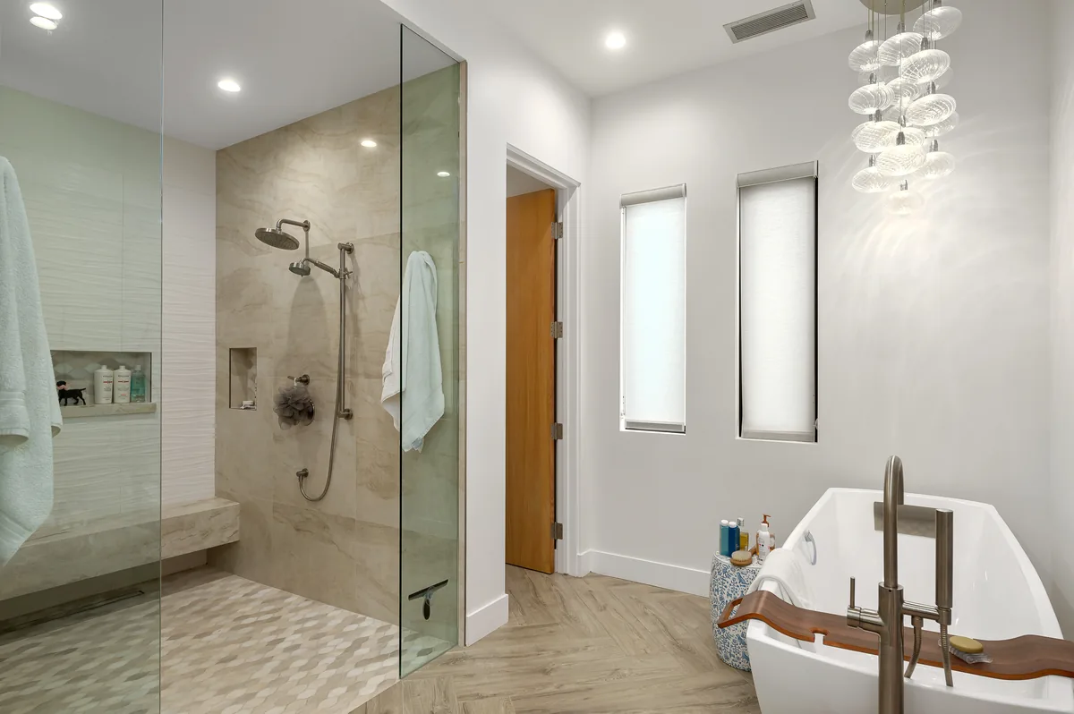 Primary bathroom with a freestanding tub, glass shower and a herringbone tile floor