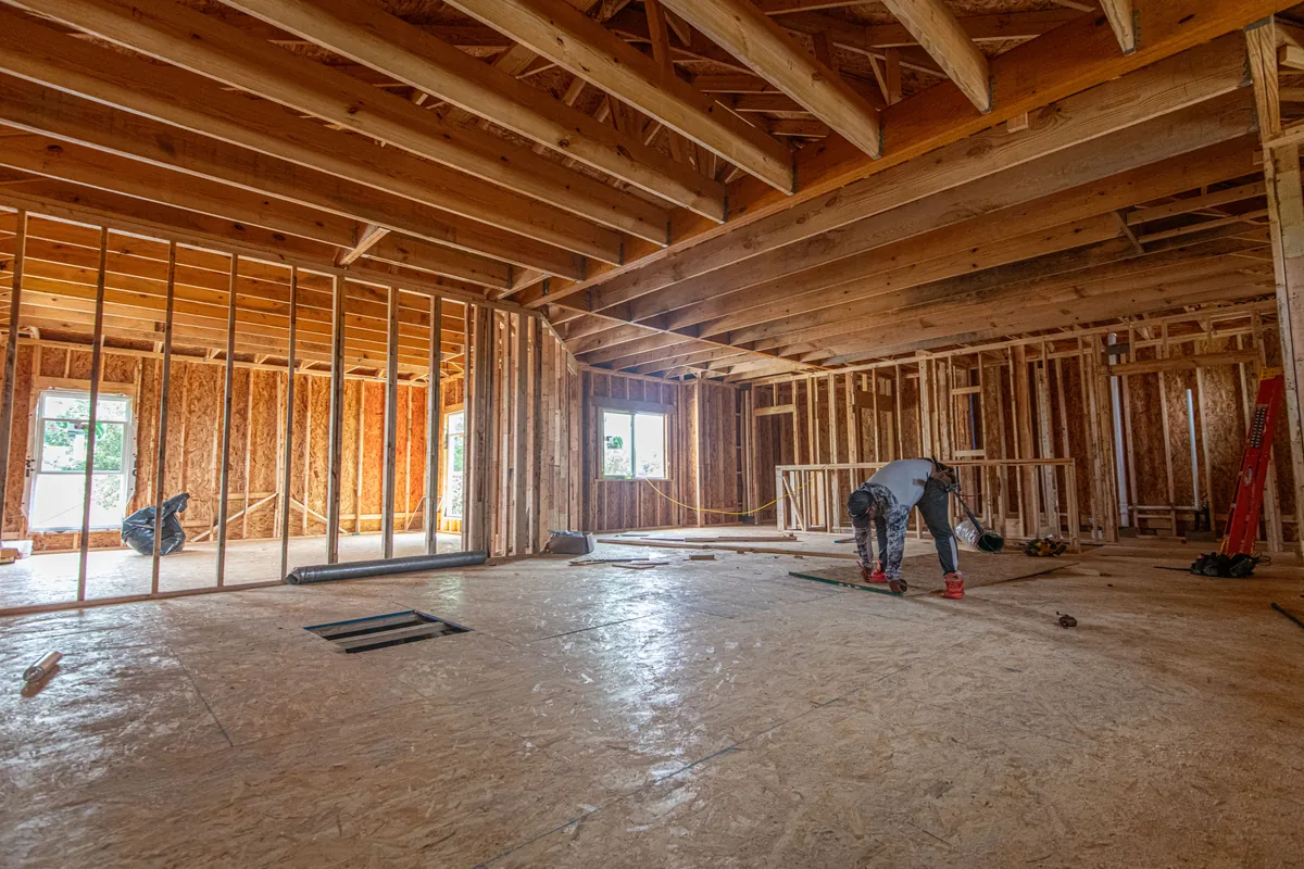 Interior of a residential home under construction, with exposed wood framing and open studs