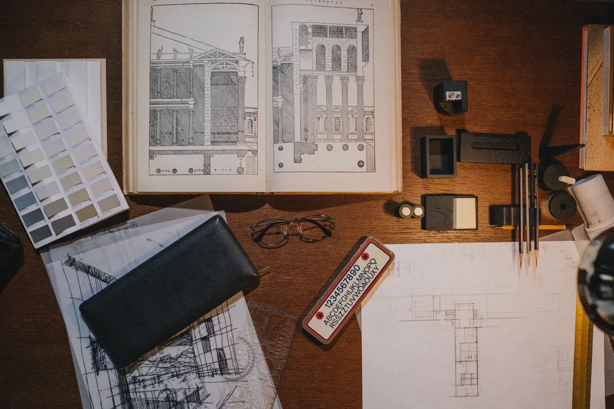 Drafting tools, material samples and architectural sketches laid out on a wooden desk