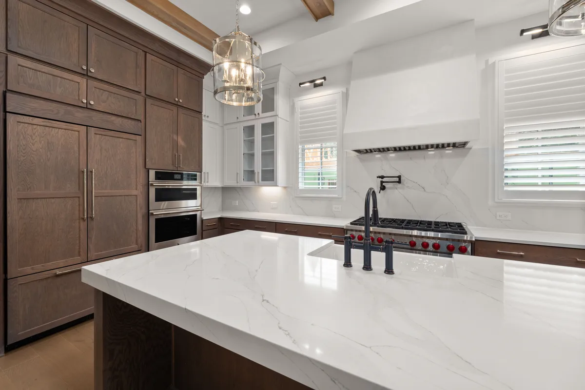 Remodelled kitchen with a marble waterfall island, dark wood cabinetry and integrated appliances