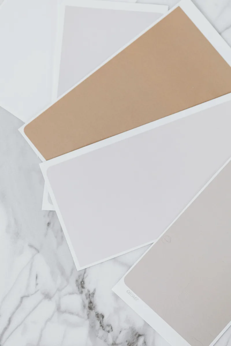 Grey and beige paint colour samples spread across a marble table